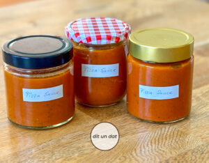 Drei Gläser mit roter Tomatensauce auf einem Holzuntergrund.