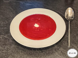 Ein weißer Teller mit Roter Beete Suppe und einem weißen Klecks Merrettich