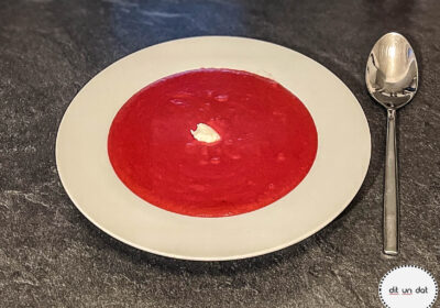 Ein weißer Teller mit Roter Beete Suppe und einem weißen Klecks Merrettich