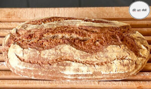 Fertig gebackenes längliches Brot auf einem Hlzgitterbrett.