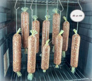 10 rot-graue Salamis hängen an Haken in einem Reifeschrank.