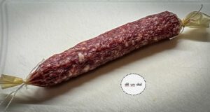 eine rötliche Salami auf einem hellen Untergrund.